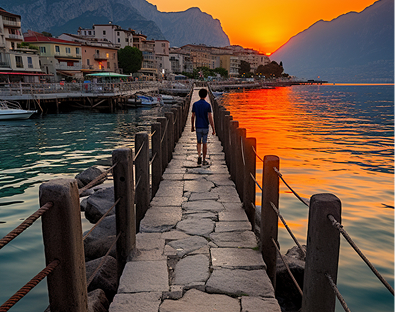 A person walks along a stone pier at sunset, set against a vibrant orange sky